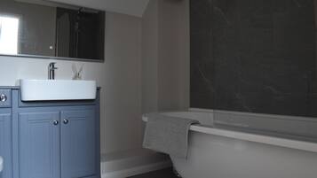 Un bagno moderno con una vasca da bagno indipendente, uno specchio grande e un mobile lavabo blu.