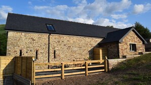A stone building with a sloped roof, a wooden fence, and a small window. - Cowshed near Abergavenny in the Black Mountains (Abergavenny)