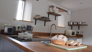 A kitchen with wooden shelves, a bread loaf, and various kitchen appliances. - Cowshed near Abergavenny in the Black Mountains (Abergavenny)