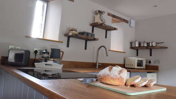 Uma cozinha com prateleiras de madeira, um pão e diversos eletrodomésticos.