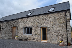 A stone building with a sloped roof, a wooden door, and a window.