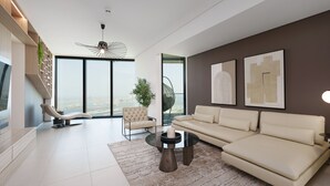 A modern living room with a sofa, armchair, and coffee table, large windows, and artwork on the walls. - Maison Privee - Lavish Apt w/ Stellar Ocean Views in Address JBR (Dubai)
