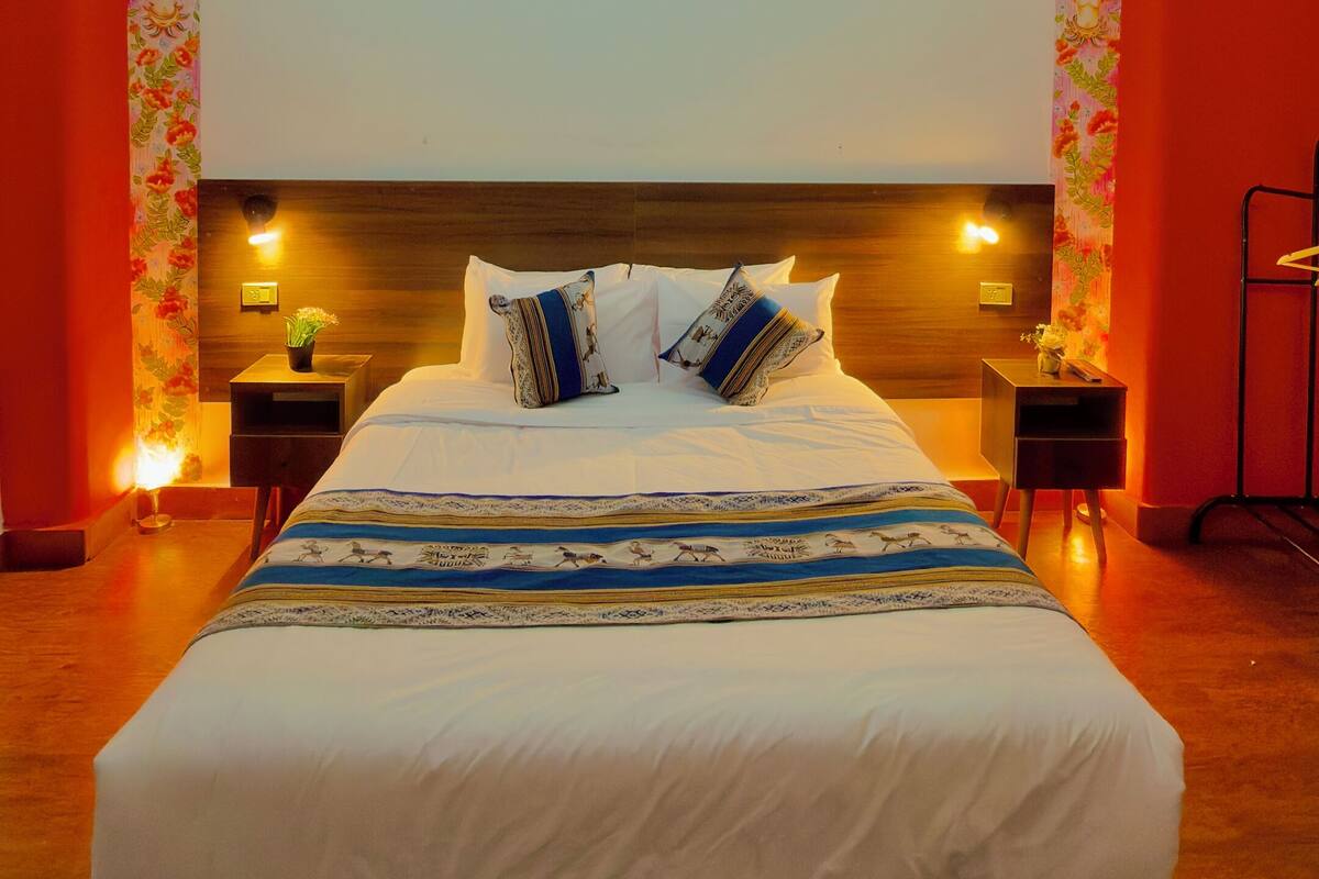 Een slaapkamer met een groot bed, twee nachtkastjes en een decoratieve plafondlamp.