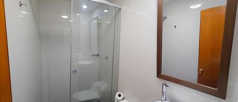 Uma casa de banho moderna com cabine de duche em vidro, sanita e lavatório com espelho em cima.