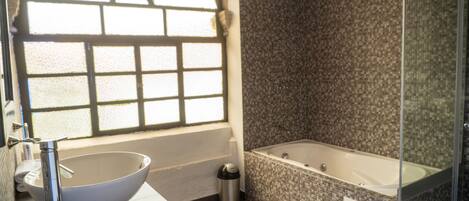 A bathroom with a large sink, a bathtub, and a window with a decorative design.