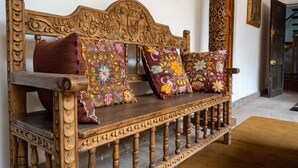 Een houten bank met sierlijke gravures en kleurrijke bloemenkussens.