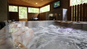 Un jacuzzi con techo de madera y un televisor montado en la pared.
