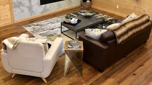 Una sala de estar acogedora con chimenea, televisor y un amplio ventanal con cortinas.