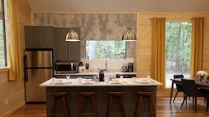 Una cocina moderna con una isla central, taburetes de bar y un comedor con mesa y sillas.