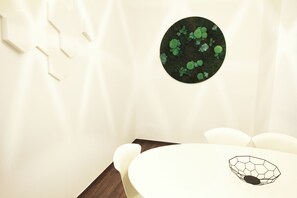 A modern dining area with a round table, white chairs, and a hexagonal bowl on the table.