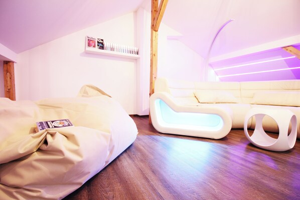 Un dormitorio moderno con techo de madera, sofá blanco y una lámpara original.
