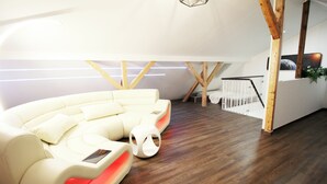 Un soggiorno moderno con un divano bianco curvo, travi in legno e una scala.