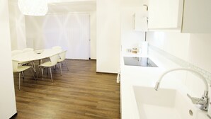 Una cucina moderna con mobili bianchi, un lavello e un'area pranzo con tavolo e sedie.