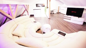 Un soggiorno moderno con un divano bianco curvo, una TV a schermo piatto e una struttura a soffitto in legno.