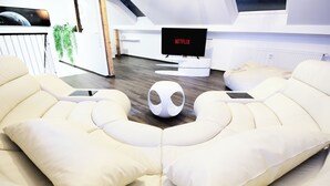 Un soggiorno moderno con un divano bianco, un tavolino da caffè bianco e originale e una TV a schermo piatto che mostra 