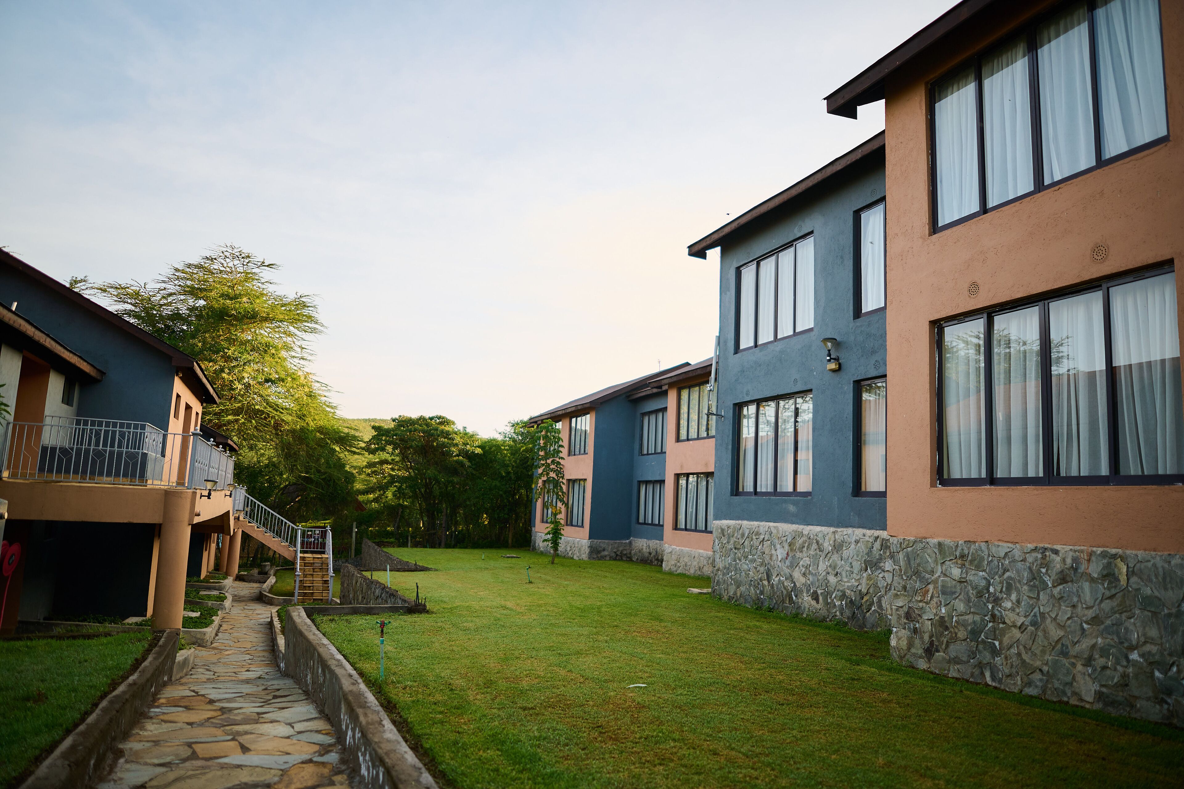 A pathway leading to a building with a stone facade and a blue and beige exterior.