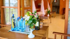 Una mesa de madera con botellas y un jarrón de flores, en una habitación con paredes de piedra y techo de madera.