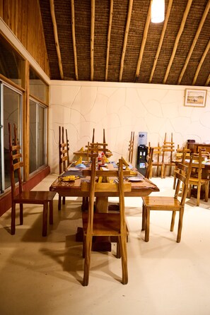 A dining area with wooden tables and chairs, a water dispenser, and a framed picture on the wall. - PELICAN LODGE - LAKE ELEMENTAITA (Gilgil)