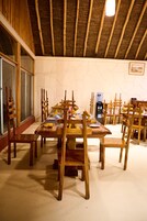Un comedor con mesas y sillas de madera, un dispensador de agua y un cuadro en la pared.
