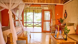 Una habitación con cama, una mesa de madera con bebidas, un sofá y vista a zonas verdes.