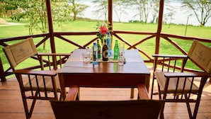 Una mesa de madera con un florero y botellas, sobre una terraza de madera con sillas que dicen 'Pelican Lodge'.