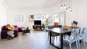 Un salón amplio con un sofá, una mesa de comedor y una televisión.