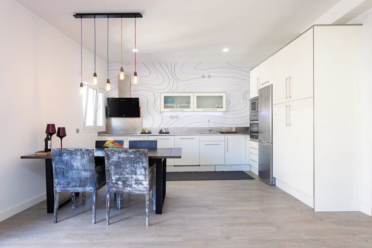 A modern kitchen with white cabinetry, a central island, and pendant lighting.