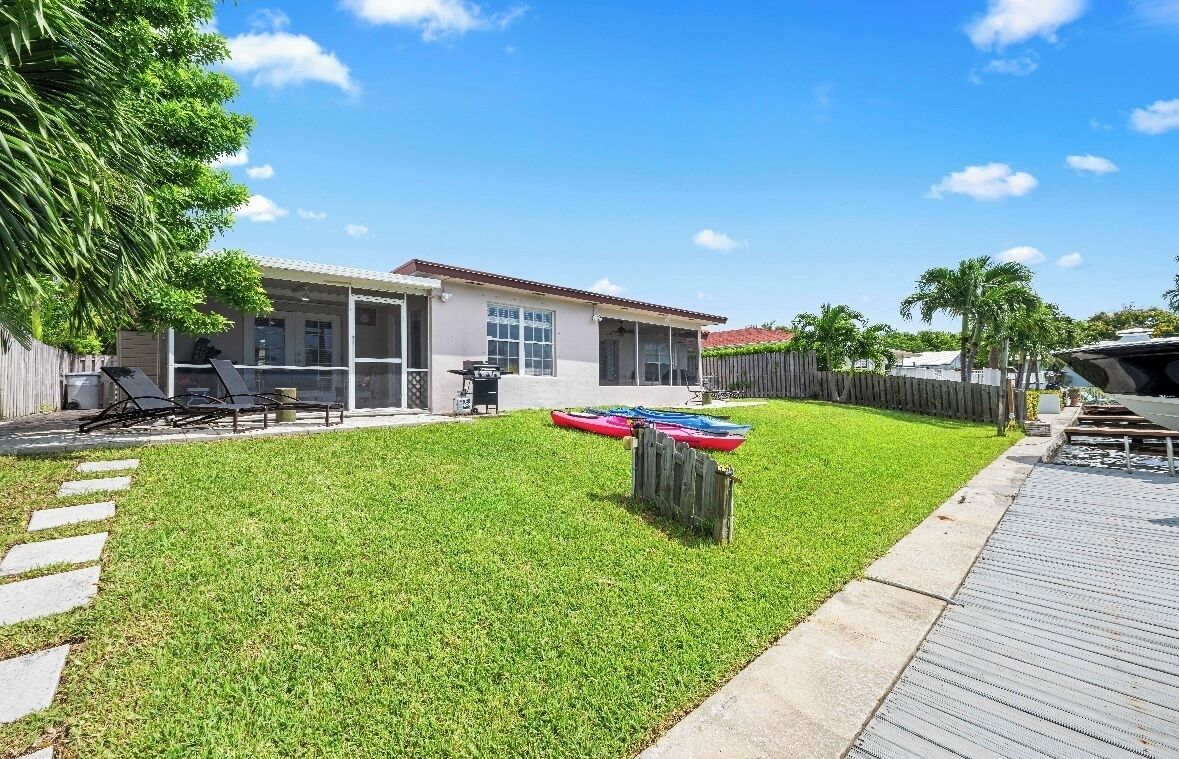 A backyard with a house, a wooden deck, and a grassy lawn.