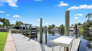 A wooden dock extending into a calm body of water, with a small white table and benches. - Waterfront-2BDR/2BTH -4 mins to the Beach+ Kayaks (Pompano Beach)