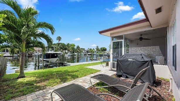 A covered outdoor area with a grill, lounge chairs, and a view of a marina with boats. - Waterfront-2BDR/2BTH -4 mins to the Beach+ Kayaks (Pompano Beach)