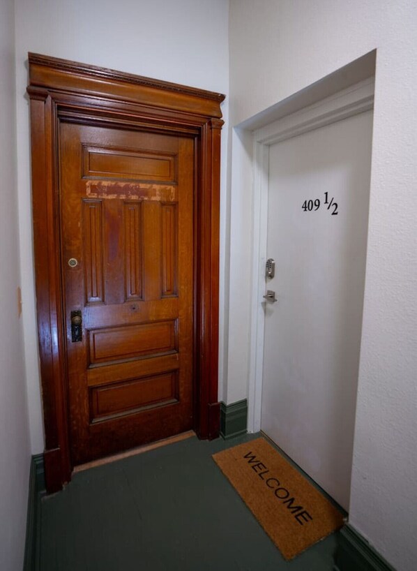 A wooden door with a brass handle and a doormat with "WELCOME" written on it. - The Getaway in DT Northfield! (Northfield)