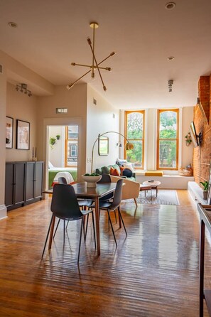 Un vaste espace de vie comprenant une table à manger, des chaises et un lustre moderne.