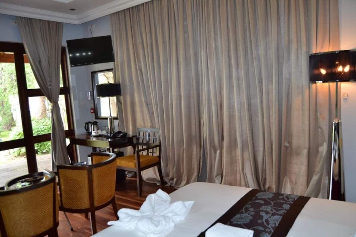 A hotel room with a bed, a desk, a chair, a television, and curtains.