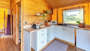 A modern kitchen with wooden walls, white cabinets, and a large window. - The Owls Hollow - UK45297 (Bishop Thornton, near Harrogate)