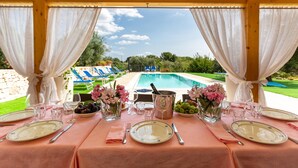 Ein Tisch, gedeckt für eine Mahlzeit, mit Blick auf einen Pool und eine Außenbereich-Sitzgruppe.