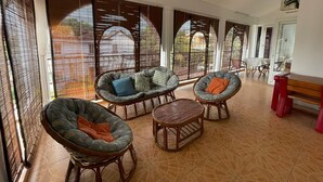 A spacious room with wicker furniture, large windows with blinds, and a tiled floor. - Villa Poisson dans L'eau (Trou-aux-Biches)