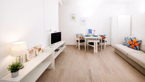 Uma sala de estar moderna com uma televisão de tela plana, uma mesa de jantar com cadeiras, um sofá e um abajur.