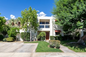 Une maison à deux étages avec un jardin devant, une allée et une boîte aux lettres.