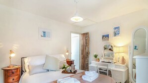 A bedroom with a bed, bedside tables, a dresser, a mirror, and a door.