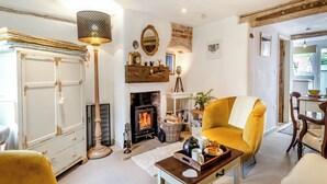 A cozy living room with a fireplace, a yellow armchair, a wooden coffee table, and a floor lamp.