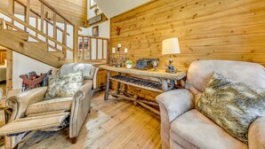 A cozy room with a wooden staircase, a plush armchair, a sofa, and a small table with a lamp. - Ruidoso Cabin w/ Deck + Views: 4 Mi to Winter Park (Ruidoso)