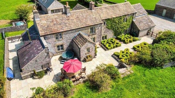 Une maison en pierre avec un grand jardin, une piscine et un espace salon extérieur.