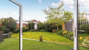 A well-maintained garden with a lawn, various plants, and a wooden fence.
