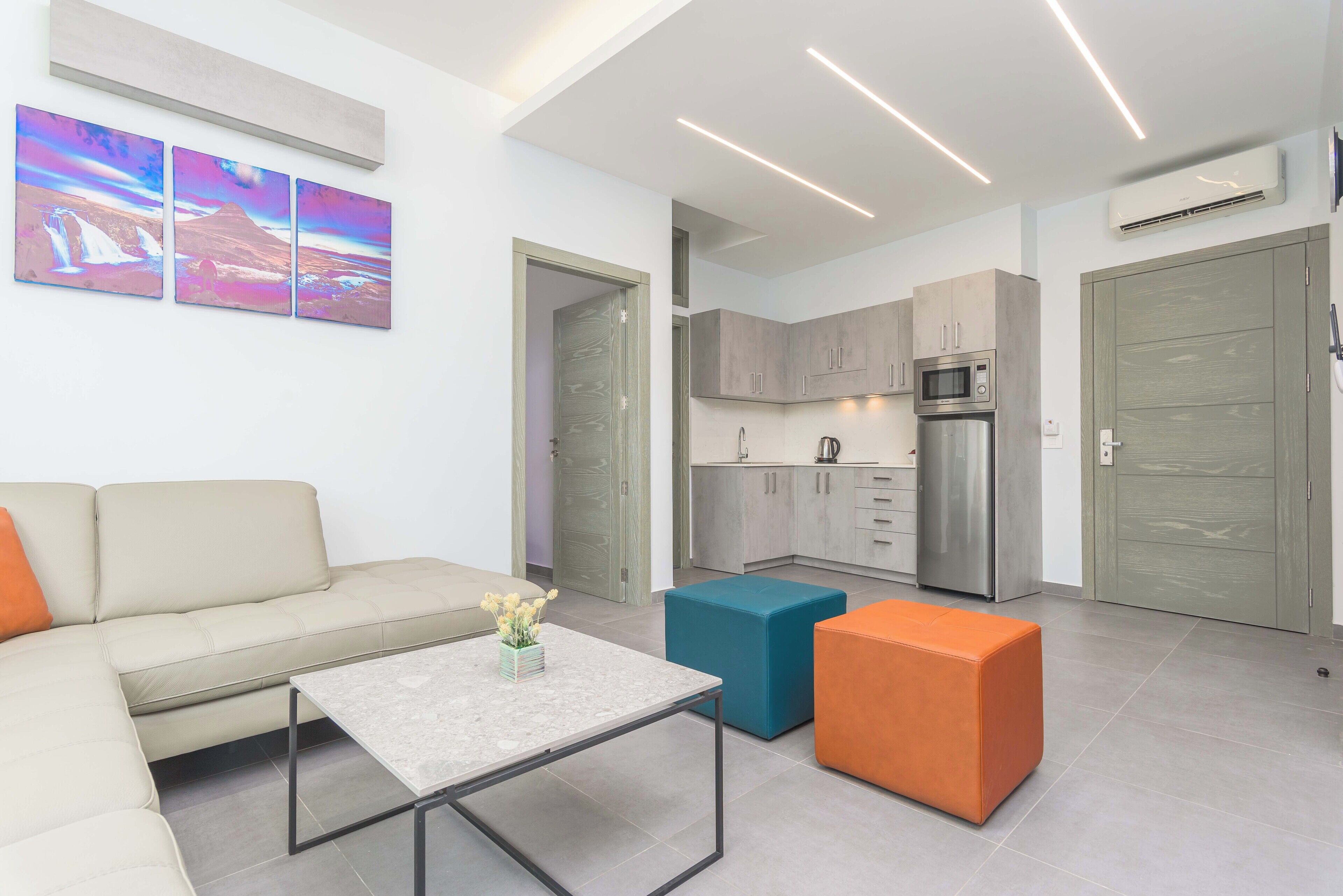 A modern living room with a sofa, a coffee table, and a kitchen area with cabinets and appliances.