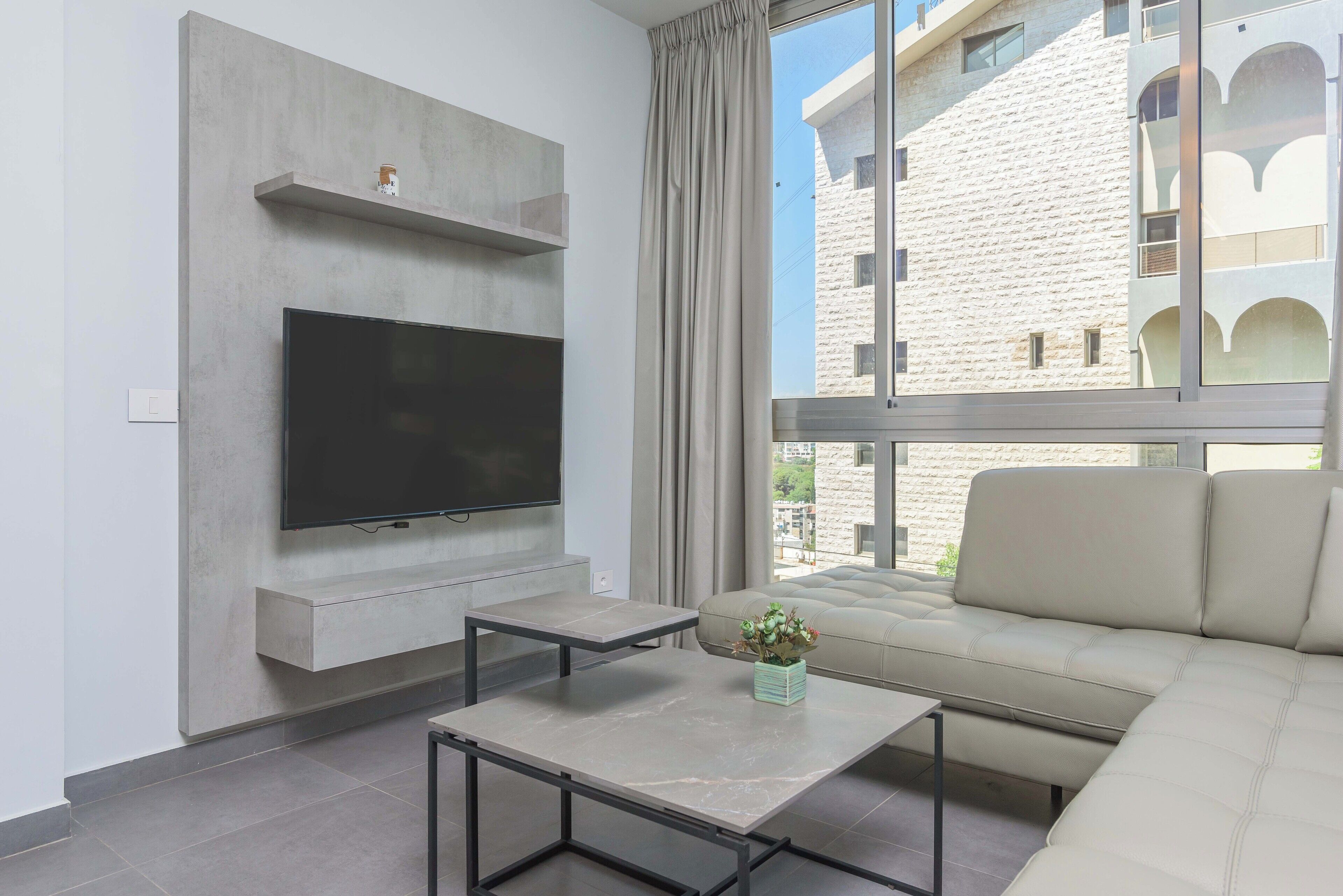 Un salon moderne avec un téléviseur à écran plat, un canapé et une table basse.