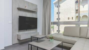 Un salon moderne avec un téléviseur à écran plat, un canapé et une table basse.