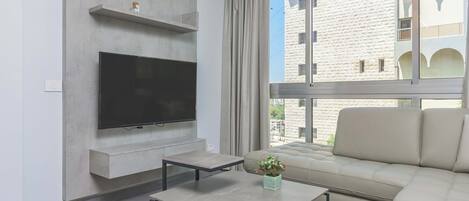 A modern living room with a flat-screen TV, a sofa, and a coffee table.