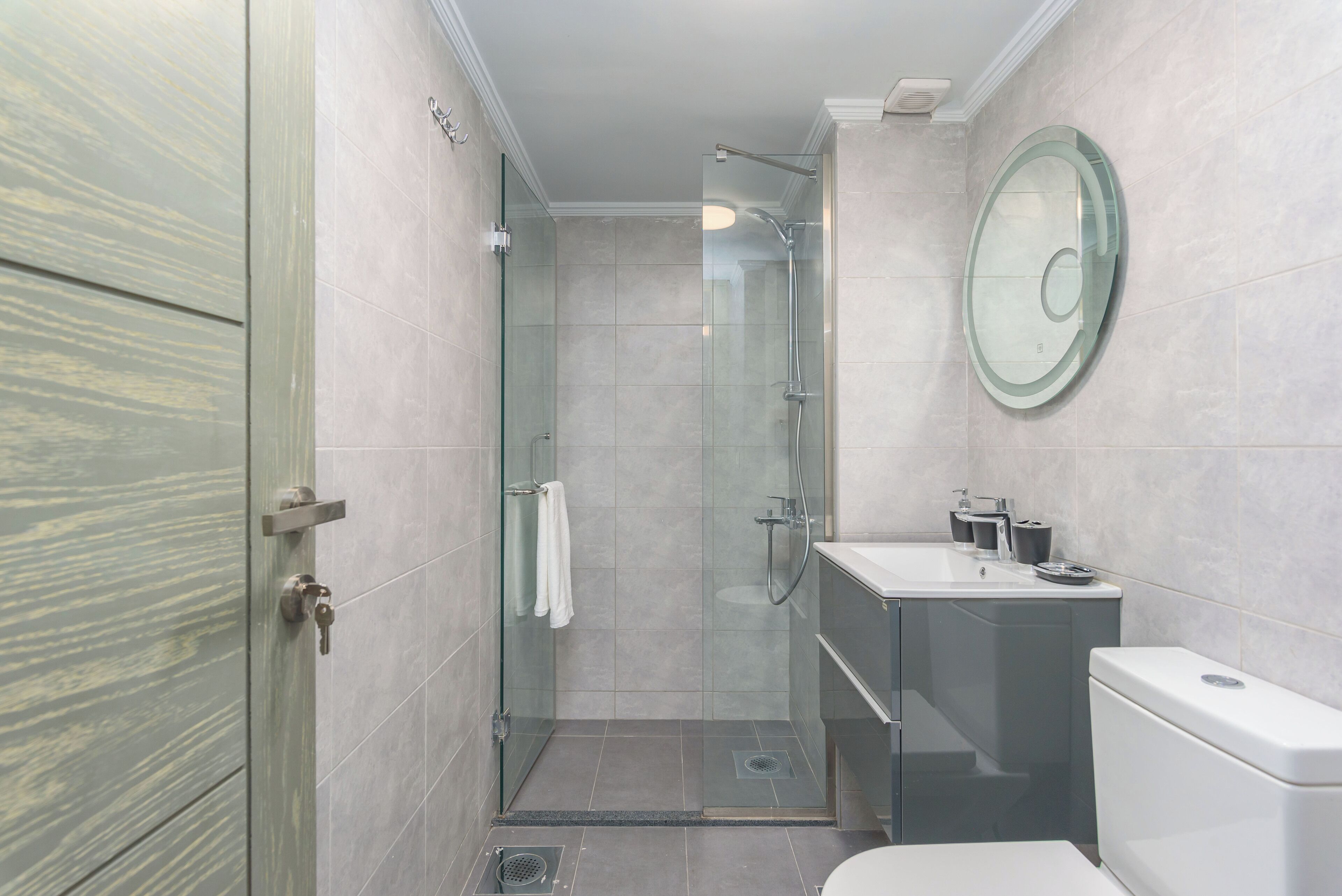 Un baño moderno con cabina de ducha de vidrio, lavabo con espejo e inodoro.