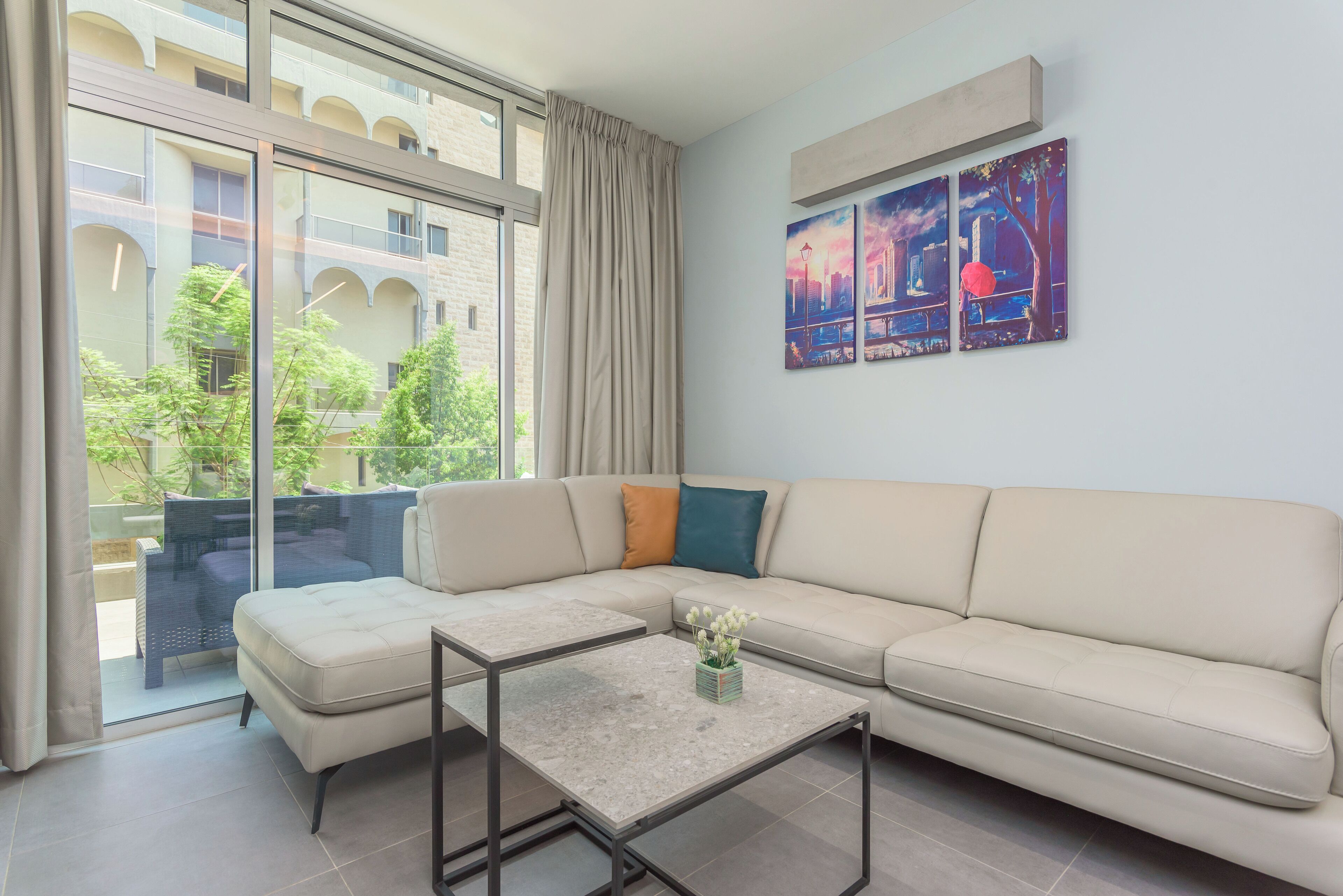 Un soggiorno moderno con un divano beige, una porta vetrata che dà su uno spazio all'aperto e un quadro appeso al muro.