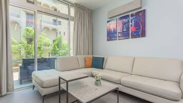 Un soggiorno moderno con un divano beige, una porta vetrata che dà su uno spazio all'aperto e un quadro appeso al muro.